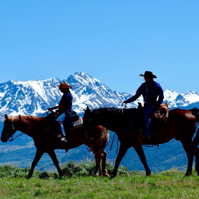 Couple enjoying a scenic horseback ride overlooking the Colorado mountains at Rusty Spurr Ranch.