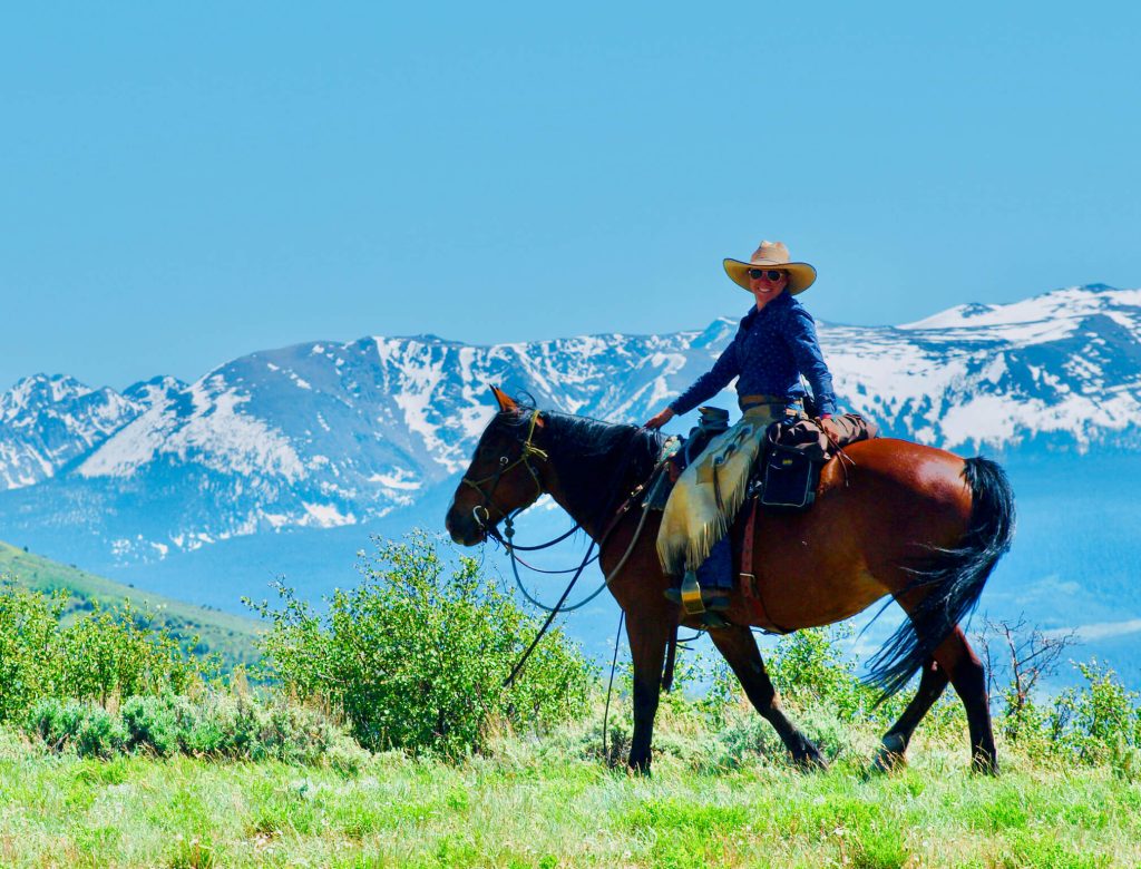 Horseback rider pausing to admire the expansive Colorado mountain views at Rusty Spurr Ranch.