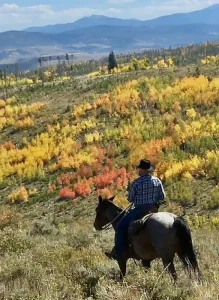 Horseback riders exploring colorful mountain trails in the Colorado Rockies during fall