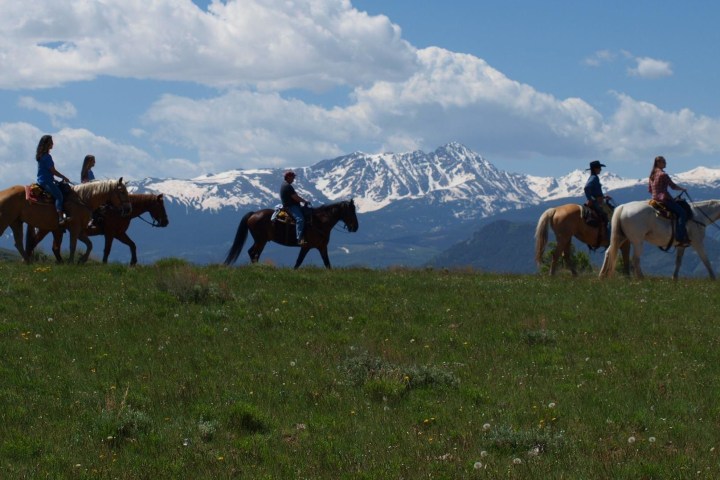 Horses and riders enjoying a calm morning ride through Colorado's mountains, embodying relaxed outdoor adventure