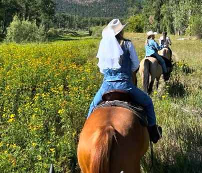 A group of women enjoys riding horses together as they celebrate a bachelorette party on the ranch.